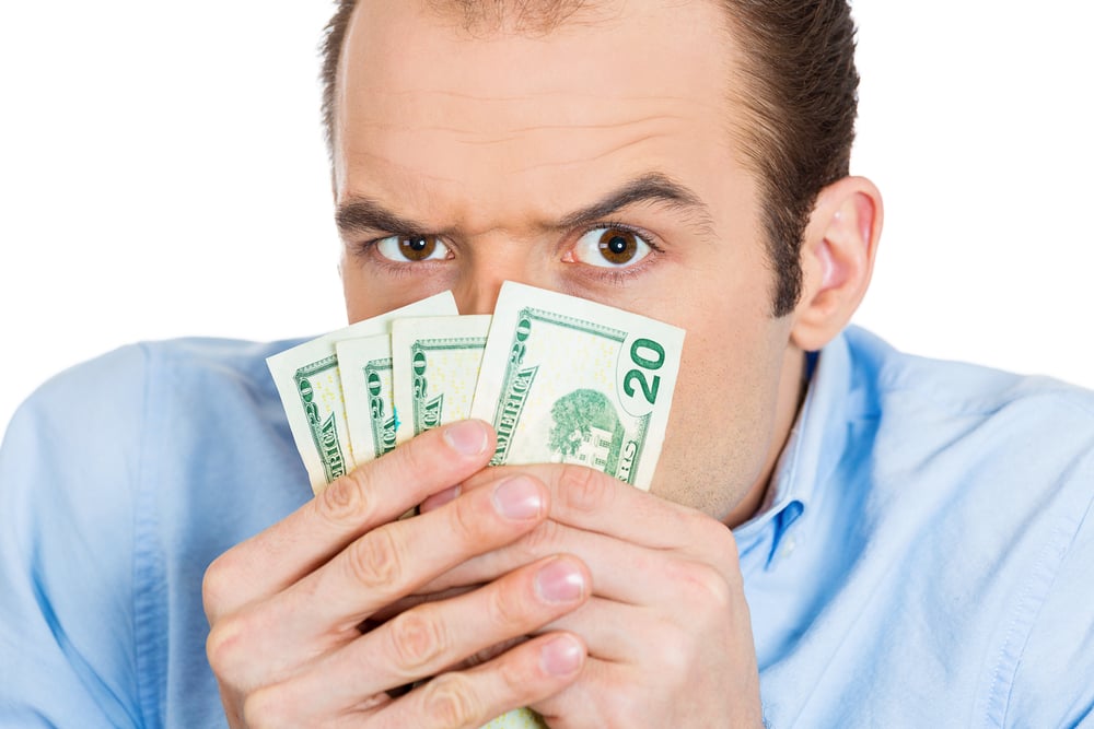 Closeup portrait of greedy banker executive CEO boss, corporate employee funny looking man, shaking holding dollar banknotes scared to loose money, suspicious isolated on white background. Expressions